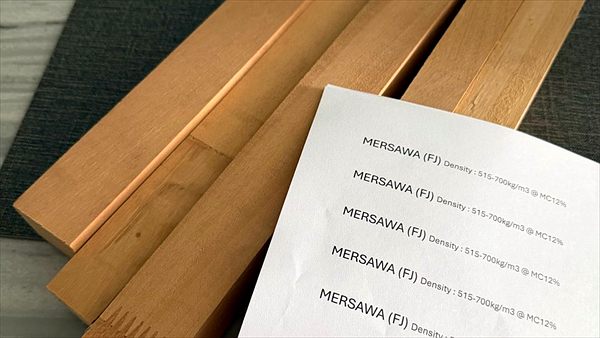 Timber moulding samples beside a printed density and moisture specification sheet