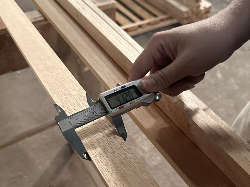Digital caliper measuring the thickness of a machined timber component